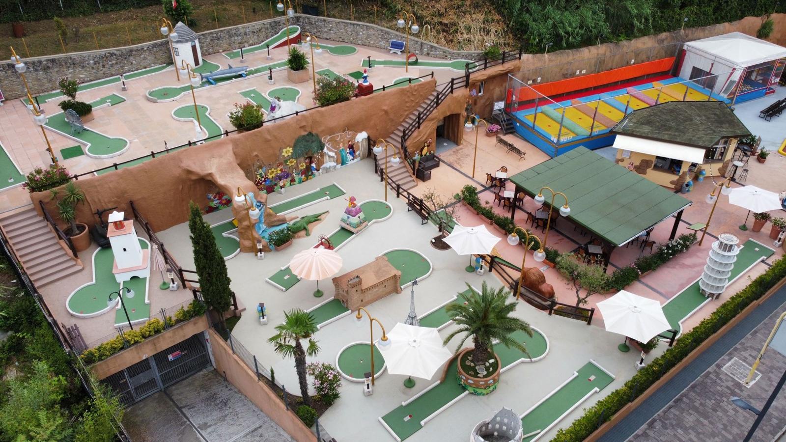 Vista aerea del Garden Golf Gabicce Mare: il percorso di minigolf a 18 buche con i suoi ostacoli a tema, i trampolini, le giostre e la pista delle macchinine
