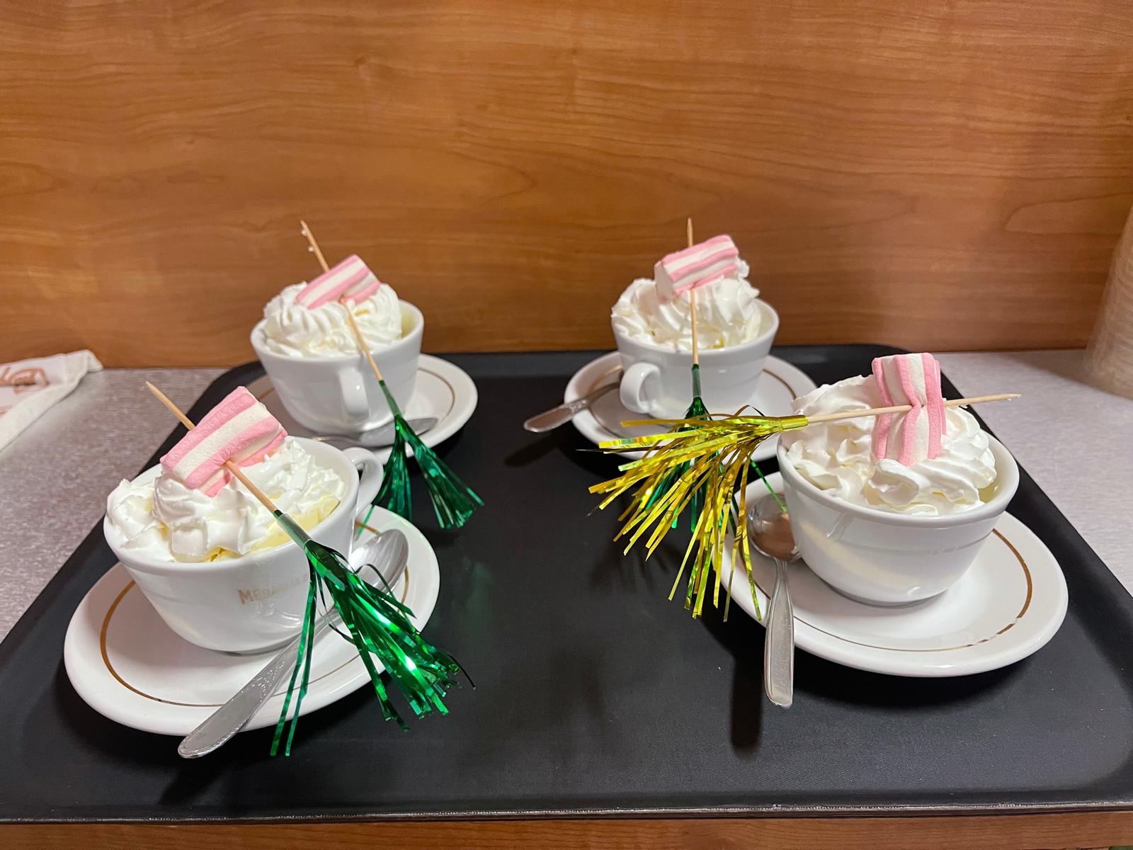 Quattro cioccolate calde con panna montata e marshmallow servite su un vassoio al bar