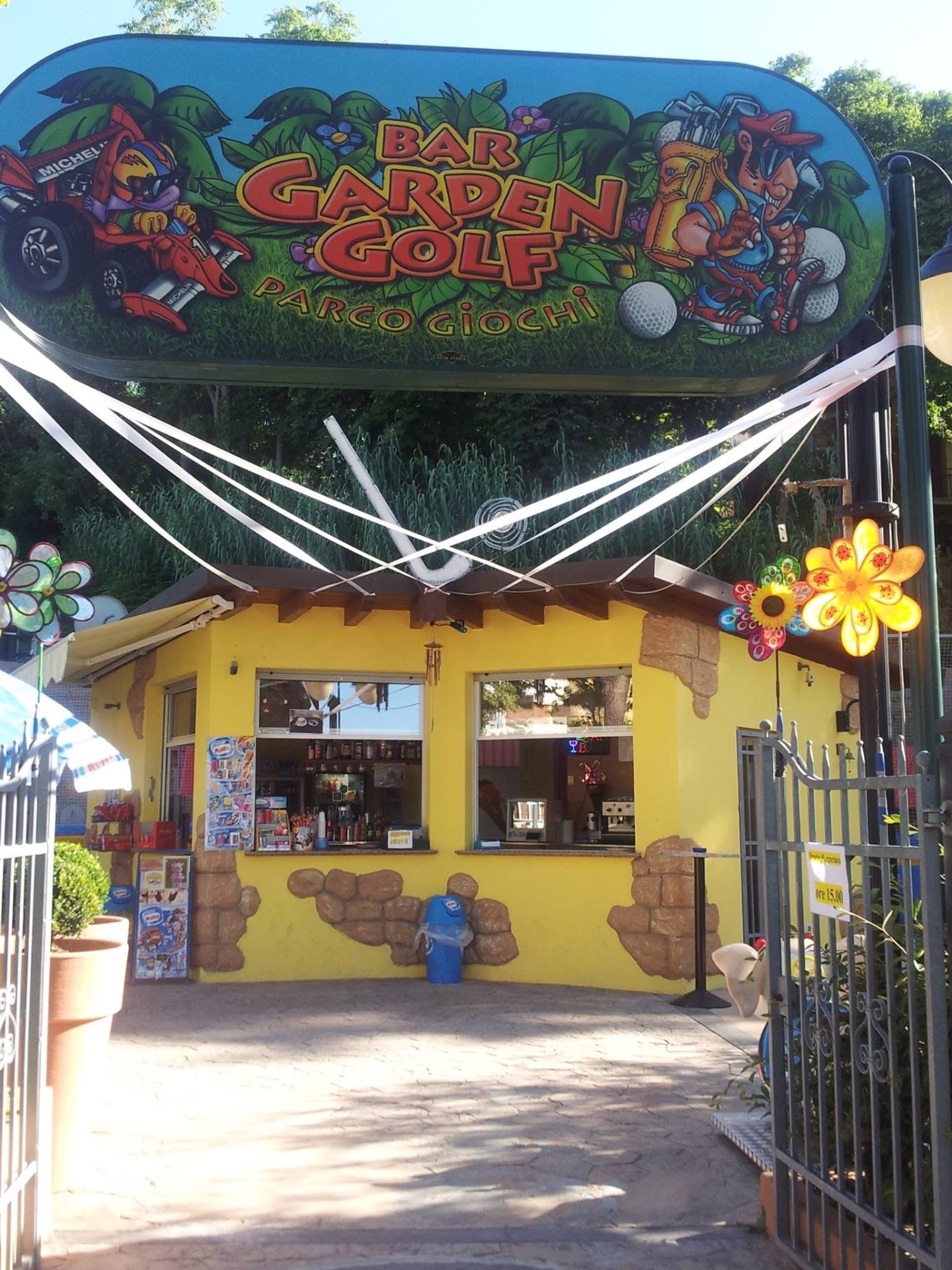 L'insegna colorata del Bar Garden Golf sopra il chiosco giallo all'ingresso del parco